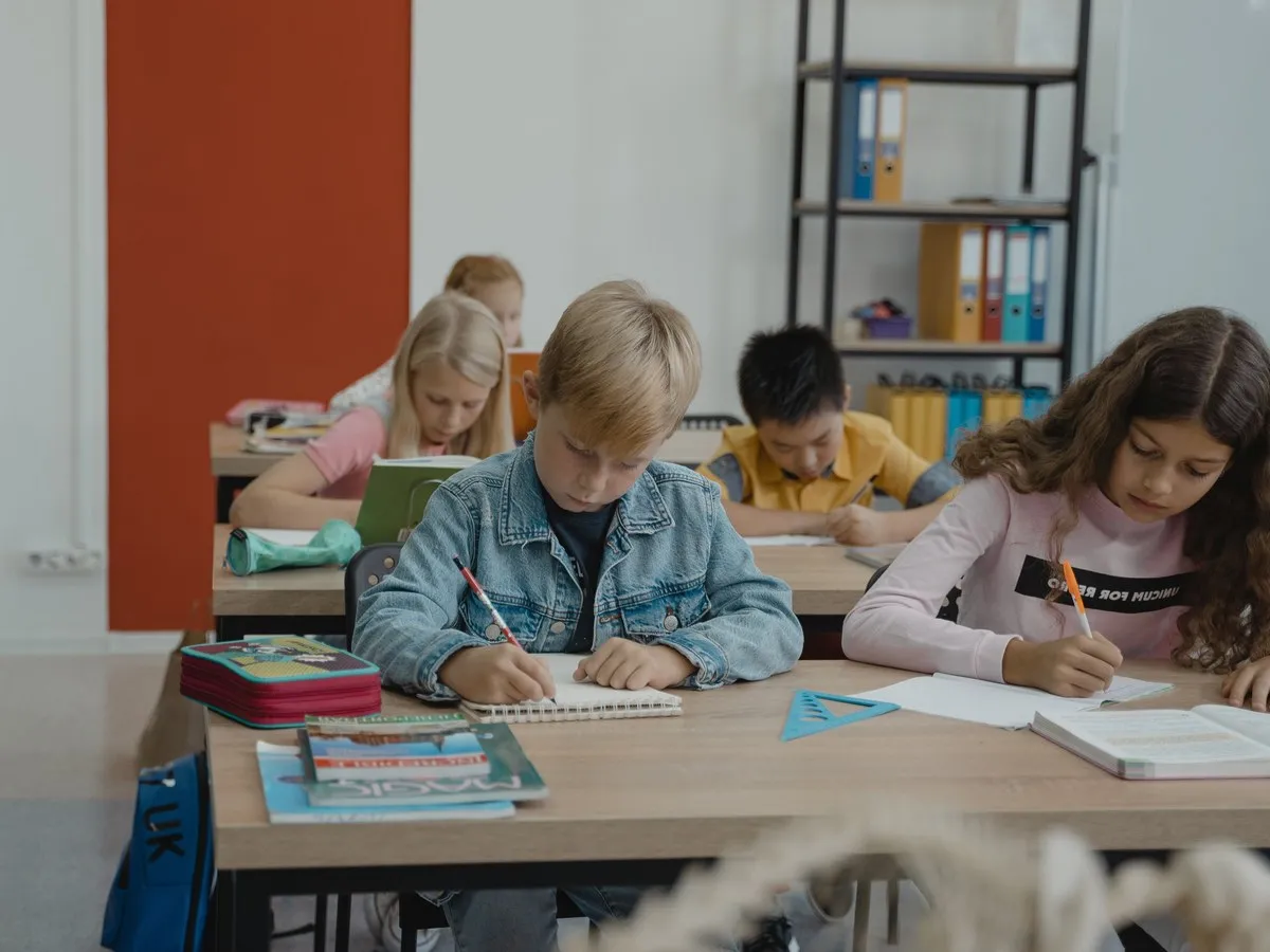 教室の机で、ノートに書きながら学んでいる子どもたち